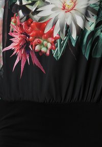 Tkanina w kwiatowy wzór z żywymi kolorami, w tym odcieniami różu i zieleni, na czarnym tle. Projekt z gumką w talii o miękkiej strukturze.