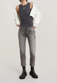 Débardeur gris côtelé, veste blanche ample, jean gris et bottines à plateforme noires. Textures présentées incluant tissu lisse et denim.
