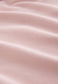 Textured pink fabric with a subtly ribbed surface, displaying soft folds and shadows, creating a gentle wave pattern throughout.