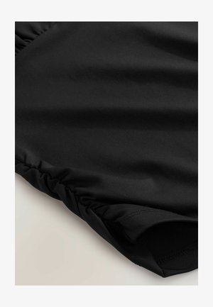 Nahaufnahme eines schwarzen Stoffs mit gesammelter elastischer Naht am Rand, die Textur und Naht zeigt.