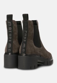 Bruna mockaskinnsankelboots med elastiska sidopaneler och en kraftig klack. Har en svart logotyp på en tygslinga bak.