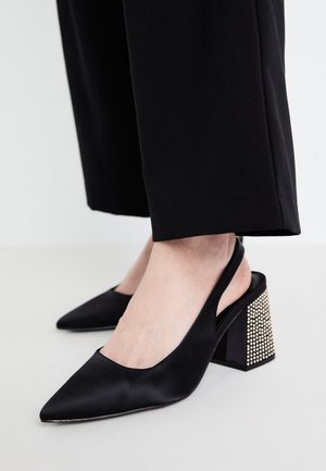 Schwarze Satin-Slingbacks mit einer spitzen Zehenpartie und einem Blockabsatz, verziert mit silbernen Nieten für zusätzliche Details.