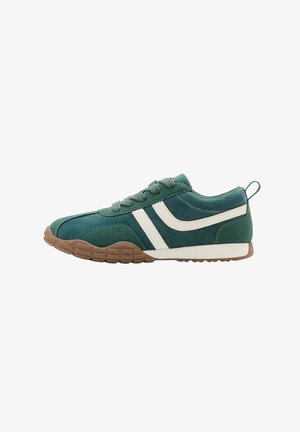 Grøn ruskinds-sneaker med hvide sidelommer, brun tekstureret sål, snørebånd og en trækkende fane på hælen mod hvid baggrund.