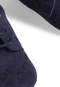 Scarpe in suede blu navy con dettagli perforati e cuciture a contrasto. Presentano una tradizionale allacciatura e un design con punta arrotondata.