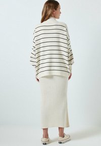 Kreemivärvi kudum, millel on tumesinised triibud, laia lõikega ja kõrge kaelusega. Koos kreemivärvi ribakudumi midi-seeliku ja beežide tossudega.