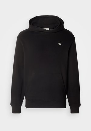 Zwarte hoodie met een buidelzak, ribgebreide manchetten en onderkant. Heeft een klein geborduurd logo op de borst. Zachte stofstructuur.