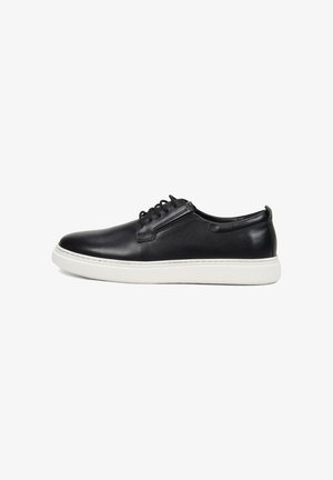 Zwarte leren lage sneaker met witte rubberen zool en zwarte veters, zijaanzicht tegen een witte achtergrond.