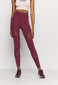 Leggings burdeos con paneles de malla y una cintura alta, combinados con un top corto rosa claro, adecuados para ropa deportiva.