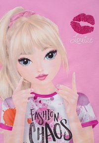 Illustrazione di una ragazza con capelli biondi in uno scrunchie rosa, che indossa una maglietta con "FASHION CHAOS" in nero, caratterizzata da schizzi colorati.