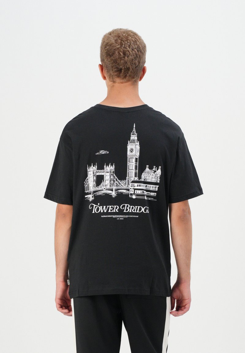 Tricou de bumbac negru cu o ilustrație albă a Podului Tower, a ceasului Big Ben și a unui autobuz cu etaj pe spate. Design casual.