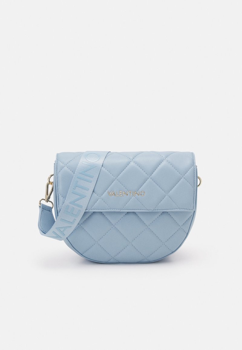 Ljusblå quiltad läderväska med rundad form, knappstängning och guldfärgad beslag. Har en rem med upphöjd text med varumärkesdesign.