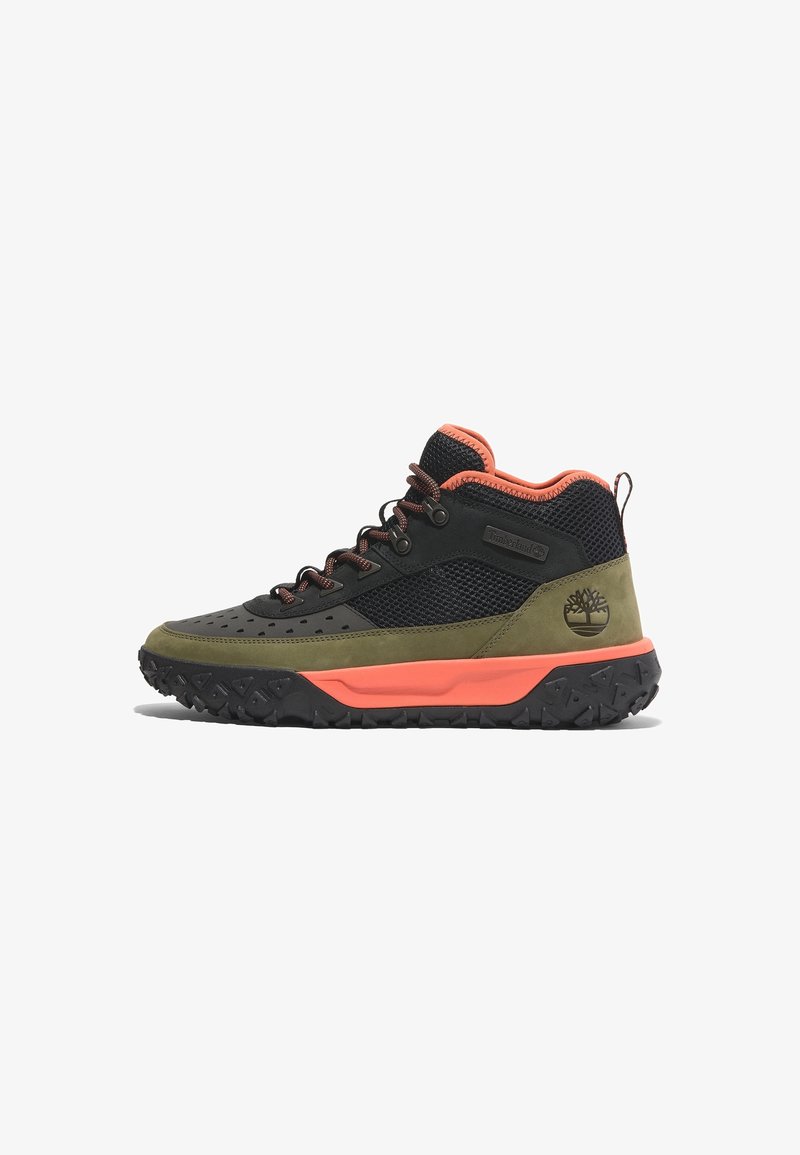 Chaussure outdoor mid-top en suède vert olive, mesh noir, accents orange, semelle noire robuste et logo Timberland au talon.