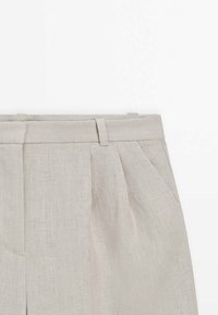 Pantalon en lin beige clair avec passants pour ceinture, plis à l'avant et poches latérales sur fond blanc.