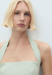 Top halter neck verde chiaro realizzato in un tessuto testurizzato. Scollo quadrato e spalline larghe, con un design minimalista. Aspetto liscio.