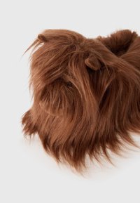 Brun pälsig mjukisdjur med långt, texturerat hår och små rundade öron, med en naturlig design och varma färgtoner.