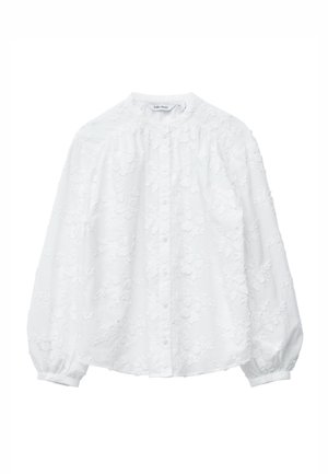 Blouse blanche avec broderie florale, fermeture à boutons, col montant et manches bouffantes. Confectionnée en tissu texturé avec une sensation douce et légère.