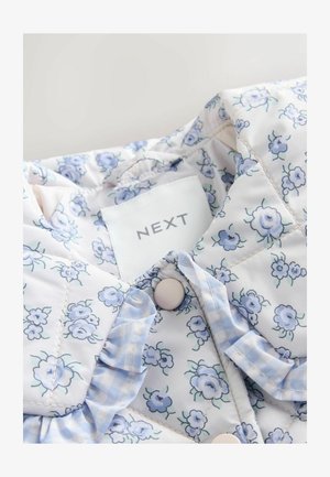 Jachetă din material matlasat cu imprimeu floral deschis în nuanțe de albastru și alb. Prezintă un guler cu volane, nasturi și o etichetă "NEXT".
