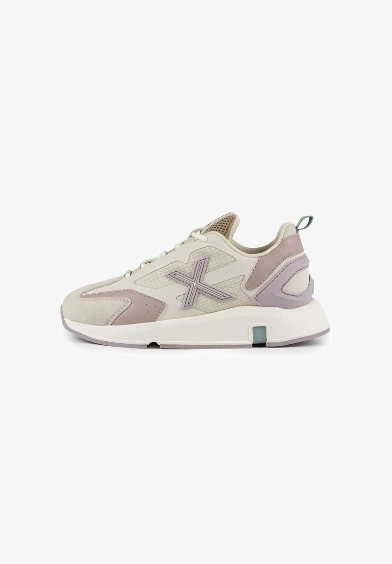 Chaussure de sport beige clair avec des accents roses, des panneaux en maille et du daim texturé. Elle présente une semelle épaisse et un logo bien visible sur le côté.