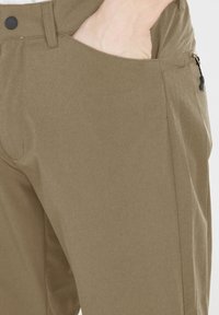 Ljust bruna byxor med en mjuk textur, med en zippered ficka på sidan och en knappstängning i midjan.