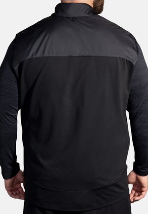 Schwarze Sportjacke mit glattem Oberteil und strukturierten unteren Ärmeln. Verfügt über einen hohen Kragen und ein schmal geschnittenes Design.