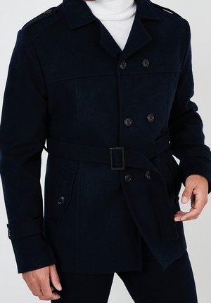 Marineblaue Wollmischungsjacke mit doppelreihigem Design, geknöpftem Vorderteil, tailliertem Gürtel und zwei Seitentaschen. Mit Schulterklappen.
