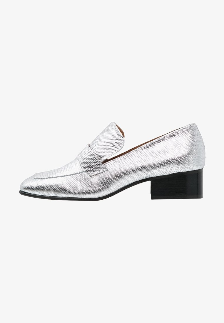 Mocassin en cuir argenté avec une finition texturée, bout pointu et petit talon carré noir. Dispose d'une large bride sur le cou-de-pied à l'avant.