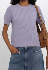 Maglione lilla a maglia con maniche corte, trama a coste, scollo rotondo, abbinato a una gonna di jeans e una borsa a tracolla marrone.