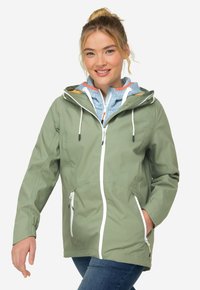 Světlá zelená bunda s kapucí, předním zipovým zapínáním a dvěma bočními kapsami na zip. Obsahuje modrou vnitřní vrstvu s vzorovanou texturou.