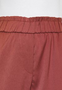 Bordeaux elastische tailleband broeken van een gladde stof, met een zijzak en een subtiele textuur in het materiaal.