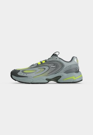 Chaussure de sport grise et verte fluo avec fermeture à lacets, semelle texturée et logo sur le côté, montrée de profil sur fond blanc.