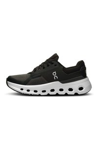 Schwarzer Sportschuh mit strukturiertem Obermaterial, weißer Zwischensohle und auffälligen hexagonalen Ausschnitten in der Sohle. Verfügt über robuste Schnürsenkel und ein Logo.