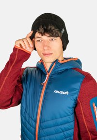 Blue and red insulated jacket with orange accents, ribbed black beanie, and logo detail. Jacket features zip pockets and hood.