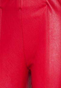 Rode leren broek met een gladde textuur. Kenmerken zijn verticale naden en een hoge tailleontwerp, wat duurzaamheid en een levendige kleur benadrukt.