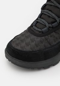 Czarne sneakersy z teksturowanym wzorem w jodełkę, zamszowym i materiałowym wykończeniem, okrągłym noskiem oraz trwałą gumową podeszwą.