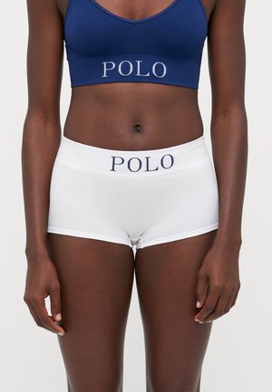 Zilas kokvilnas sporta krūšturis un baltas hipster šortas ar zilu "POLO" logo uz jostas, ar gludu tekstūru un pieguļošu dizainu.