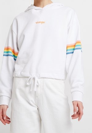 Haut cropped blanc avec le logo "Wrangler", présente des rayures arc-en-ciel sur les manches, un ourlet à cordon, une coupe décontractée et une texture de tissu douce.