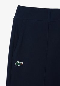 Marineblauwe broek met een gladde textuur, voorzien van een elastische tailleband, zijzakken en een accent van een groene krokodillenlogo.