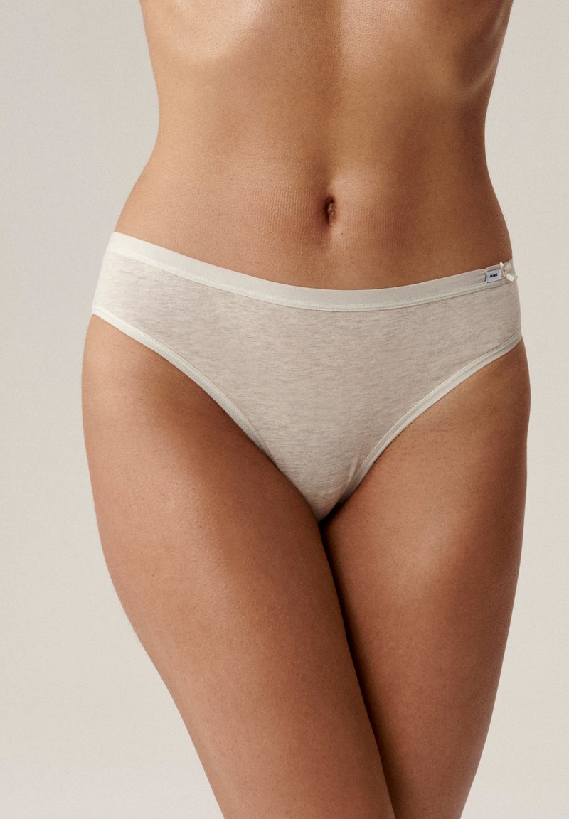 Jasno beżowe bawełniane figi o miękkiej teksturze, niskim kroju i cienkim elastycznym pasie. Posiadają mały akcent w postaci kokardki z boku.
