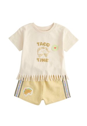Cremefarvet babyoutfit med teksten "Taco Time", smilende taco-grafik på skjorten, frynset kant og matchende shorts med taco-patch og stribet sidelæg.