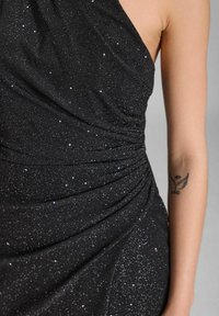 Schwarzes Kleid mit metallischem Glanz, das mit drapiertem Stoff und einem seitlichen Raffung-Design ausgestattet ist. Glatte Textur, asymmetrischer Ausschnitt und taillierte Passform.