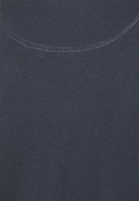 Tessuto di cotone blu navy con una consistenza liscia e un collo a girocollo, con cuciture visibili attorno al colletto. Nessun motivo o decorazione.