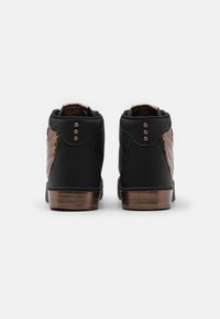 Černé vysoké tenisky s texturovanou tkaninou, bronzovými akcenty a třemi kovovými cvočky na každém patě. Plochá gumová podrážka pro lepší přilnavost.