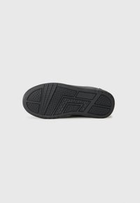 Svart sneakersula med texturerad gummi för grepp, med ett geometriskt mönster och framträdande slitbanor för ökad dragkraft.