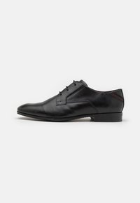 Zapato de vestir negro de cuero con un acabado liso, punta afilada, costuras mínimas y diseño de cordones. Tacón reforzado y sutil detalle de marca.