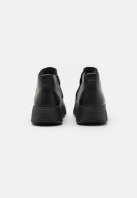 Sorte lær ankle boots med rund tå, baklukk med glidelås, og en teksturert gummisåle. Har en subtil logo detalj på hælen.