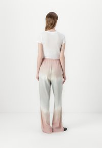 White cropped t-shirt and light pink to green gradient wide-leg pants with an elastic waist, smooth texture, and no visible patterns or hardware.