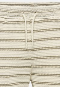 Gestreifte Creme- und Beiget�öne Shorts aus strukturiertem Stoff, mit einem Kordelzugbund und horizontalen Streifen in unterschiedlichen Breiten.