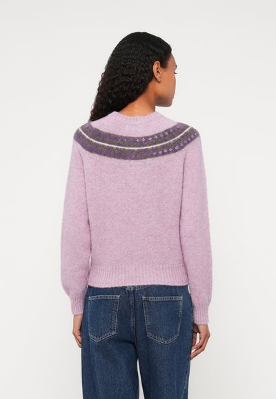 Rozā adīta džemperis ar apaļu kakla izgriezumu, kam ir rakstains yoke tumši violetā un zaļā krāsā. Mīksta, pūkaina tekstūra; ribotas apakšdaļa un piedurknes.