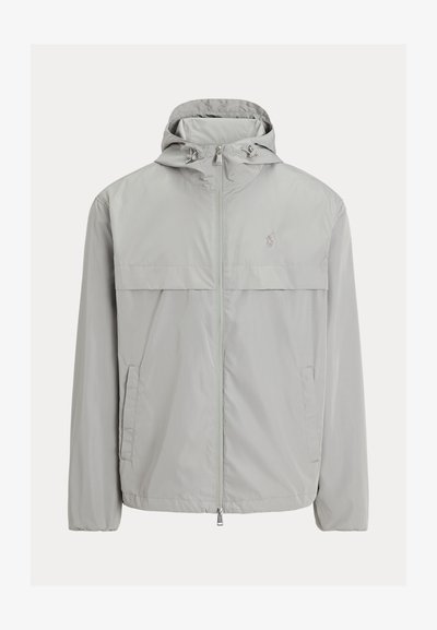 Ανοιχτό γκρι αδιάβροχο μπουφάν με κουκούλα, εμπρόσθιο φερμουάρ, δύο πλαϊνές τσέπες και οριζόντιο πάνελ στο στήθος. Διαθέτει διακριτική λεπτομέρεια με λογότυπο.