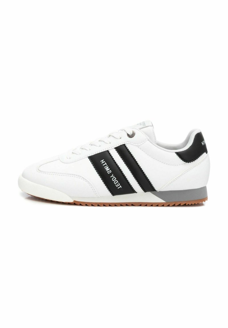 Sneaker bianca con strisce nere, dotata di una suola in gomma testurizzata, punta con lacci e accento grigio sul tallone. Logo del marchio di lato.